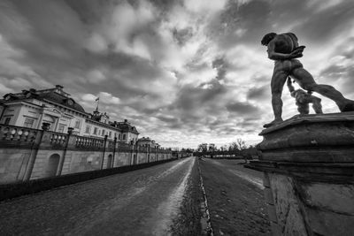 Statue by city against sky