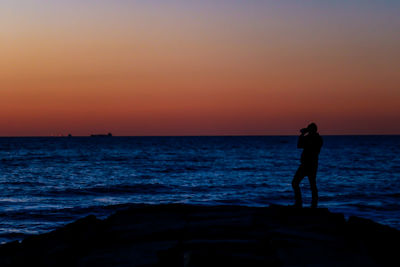 Silhouette man standing on beach during sunset