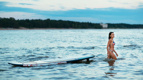 Woman in bikini on boat in sea against sky