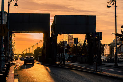 Cars on road against sky during sunset