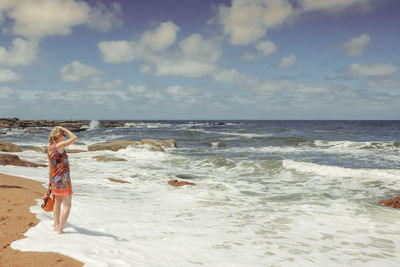 Boy standing on beach against sky