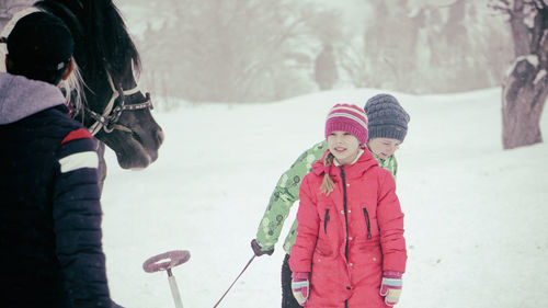 People standing by horse on snow covered field