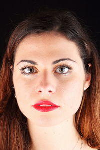 Close-up portrait of beautiful woman against black background