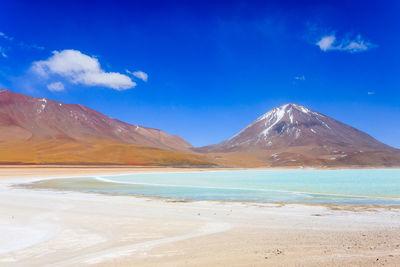 Scenic view of sea and mountains against blue sky