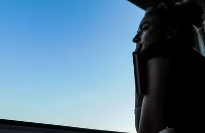 Low angle view of woman against clear blue sky
