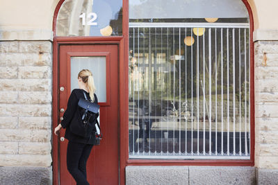 Rear view of mid adult businesswoman opening office door