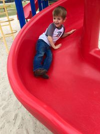 Full length of boy enjoying on slide at playground