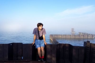 Young man looking at sea against sky