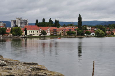 Town by river against cloudy sky