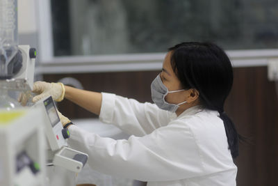 Vietnamese woman scientist operating a rotary evaporator to make an experiment in the laboratory