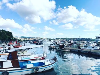 Boats moored at harbor in city against sky