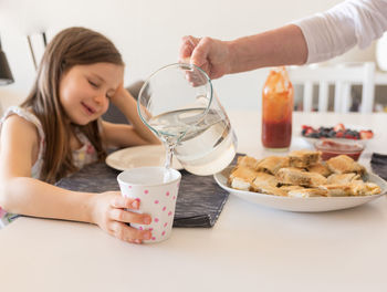 Midsection of woman holding ice cream on table