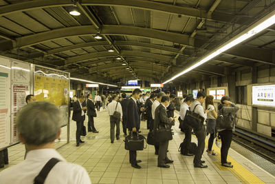 Rear view of people walking on railroad station platform