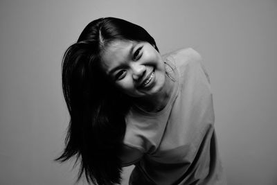 Portrait of smiling young woman against gray background