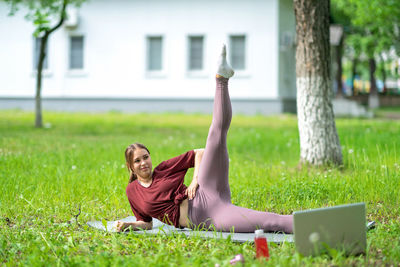 Side view of woman using laptop while sitting on field