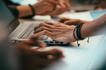 Close-up of hands using laptop in office