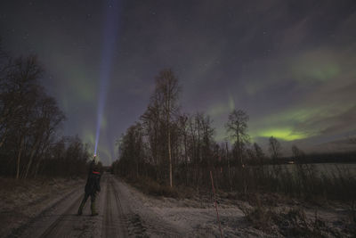 Young man lighting northern lights with his flashlight