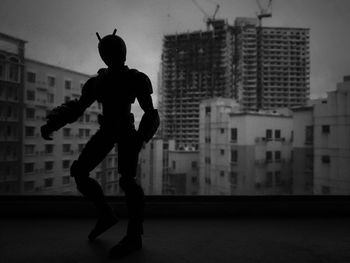 Silhouette of boy standing against buildings in city