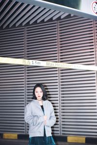 Portrait of beautiful woman standing below sign