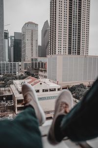 Low section of man sitting on roof in city