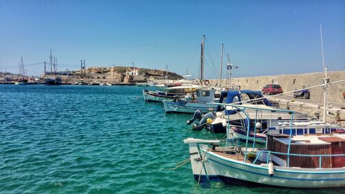 Sailboats moored on sea against clear blue sky