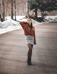 Portrait of young woman standing against trees