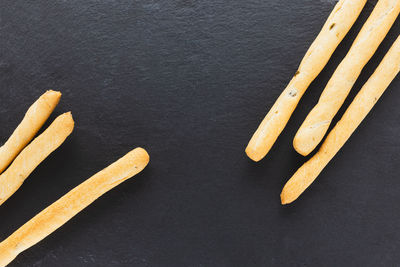 Fresh italian grissini breadsticks served on black background. dry baked bread with olive pieces