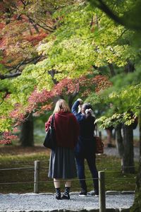 Rear view of couple standing against trees