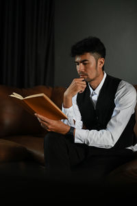 Man with hand on chin reading book