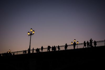 Low angle view of silhouette people on bridge against sky during sunset