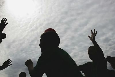 Silhouette of people against cloudy sky