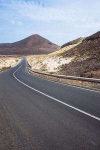 Road by mountains against sky