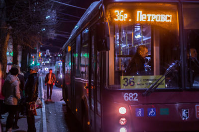 People on illuminated street in city at night