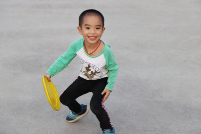 Cheerful boy playing with plastic disc at park