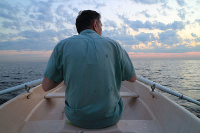 Rear view of man standing on sea against sky