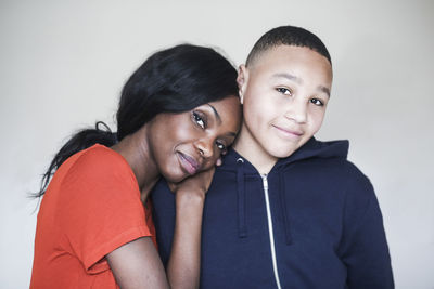 Portrait of mother resting head on son's shoulder at home