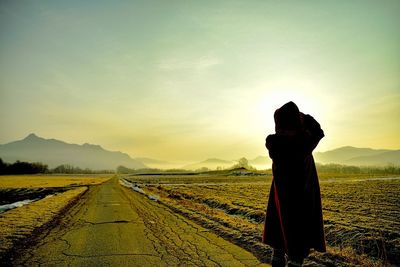 Man on landscape against sky during sunset