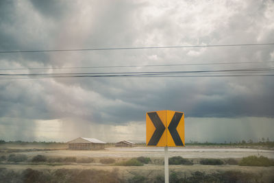 Electricity pylon on field against storm clouds