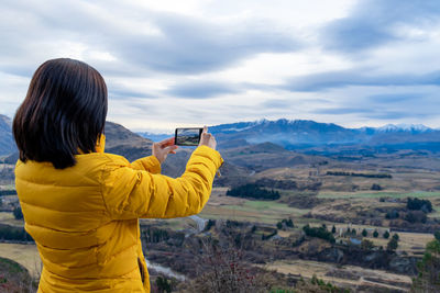Rear view of person photographing against sky