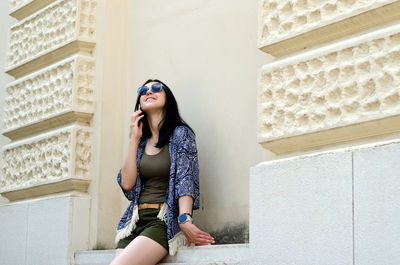 Young woman standing against wall