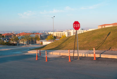 Road sign by street against sky in city