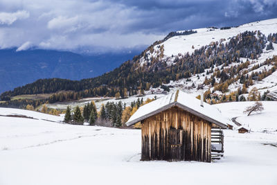 House on snowcapped mountains against cloudy sky