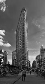 People on street by flatiron building against sky