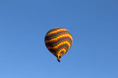 Low angle view of hot air balloon flying against clear blue sky