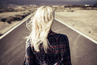 Rear view of woman standing on road