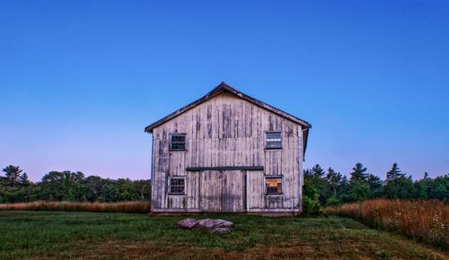 House on field against clear blue sky