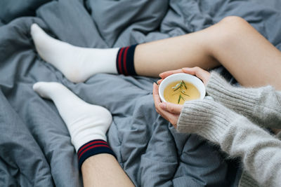 Midsection of woman holding alarm clock on bed