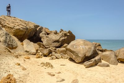 Rock formation on beach against clear sky