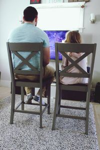 Rear view of couple sitting on chair at home