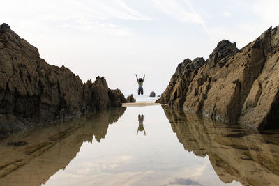 Woman jumping near water puddle under sky